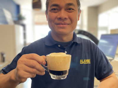 Alambe Coffee owner holding an egg coffee and smiling