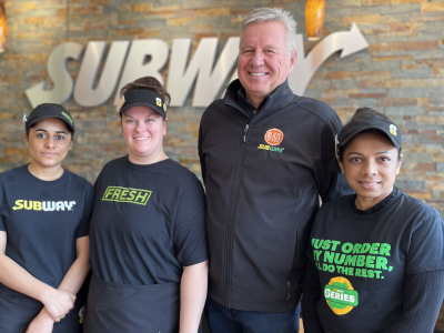 Subway staff, three women and one man smiling inside store